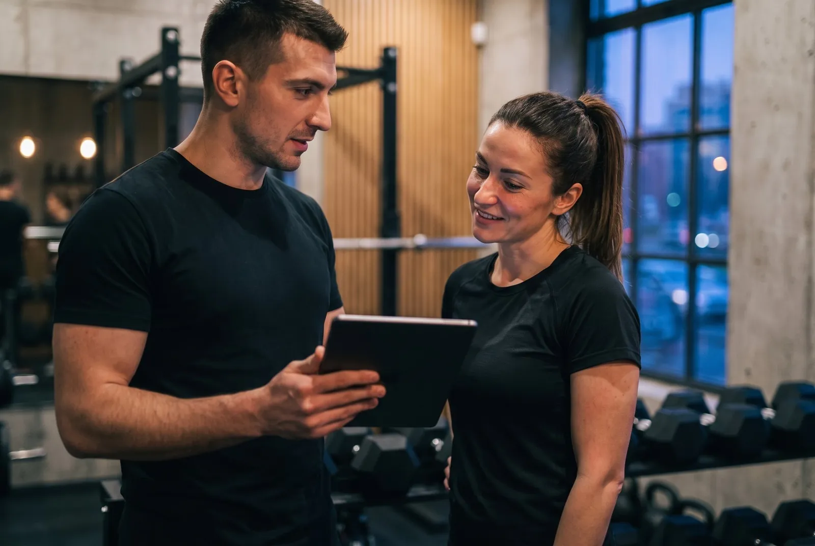 Illustration: a trainer and a member talking in the club, looking at the member profile